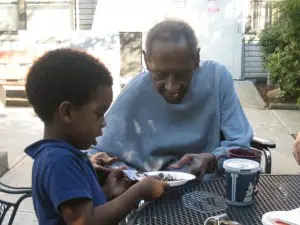 Idalio (98) cutting up a piece of his chocolate birthday cake for Michael (4)